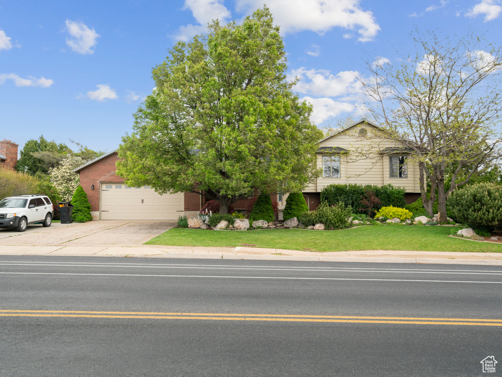 View of front facade featuring an attached garage, a front yard, brick siding, and concrete driveway
