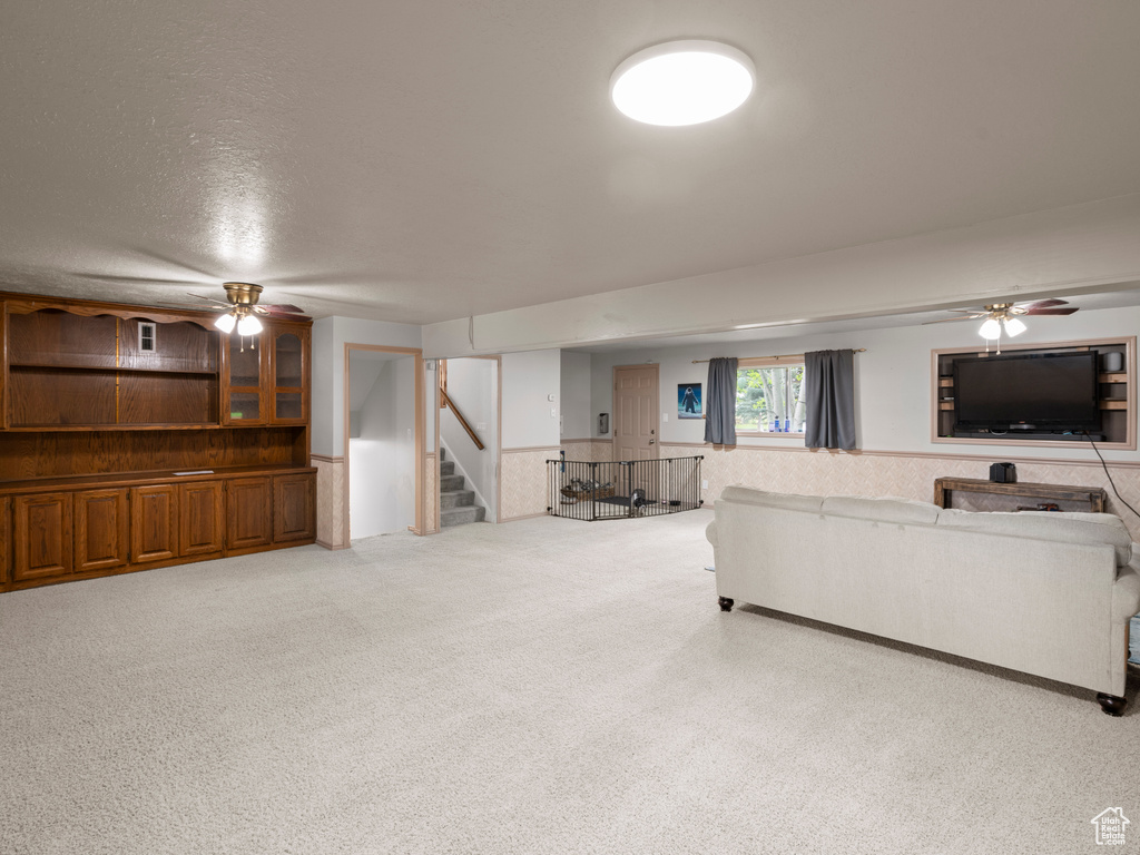 Living area featuring stairway, a wainscoted wall, and ceiling fan