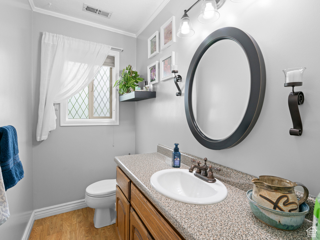 Bathroom with visible vents, ornamental molding, vanity, wood finished floors, and toilet