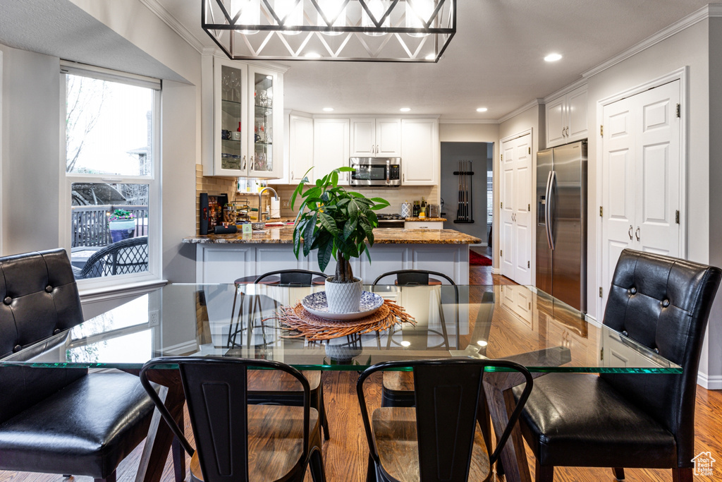 Dining space featuring baseboards, ornamental molding, recessed lighting, and wood finished floors