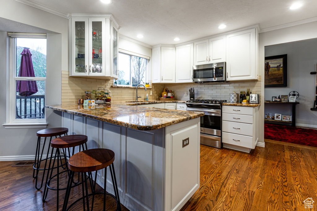 Kitchen featuring a sink, appliances with stainless steel finishes, a breakfast bar area, and white cabinets