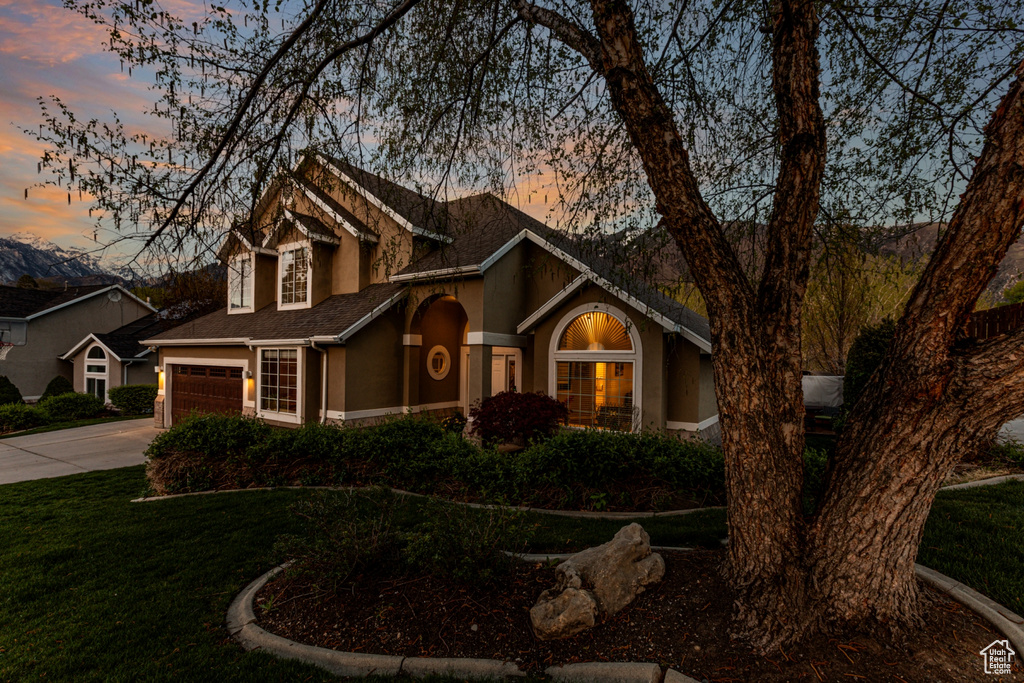 Traditional-style home with roof with shingles, stucco siding, concrete driveway, and a front yard
