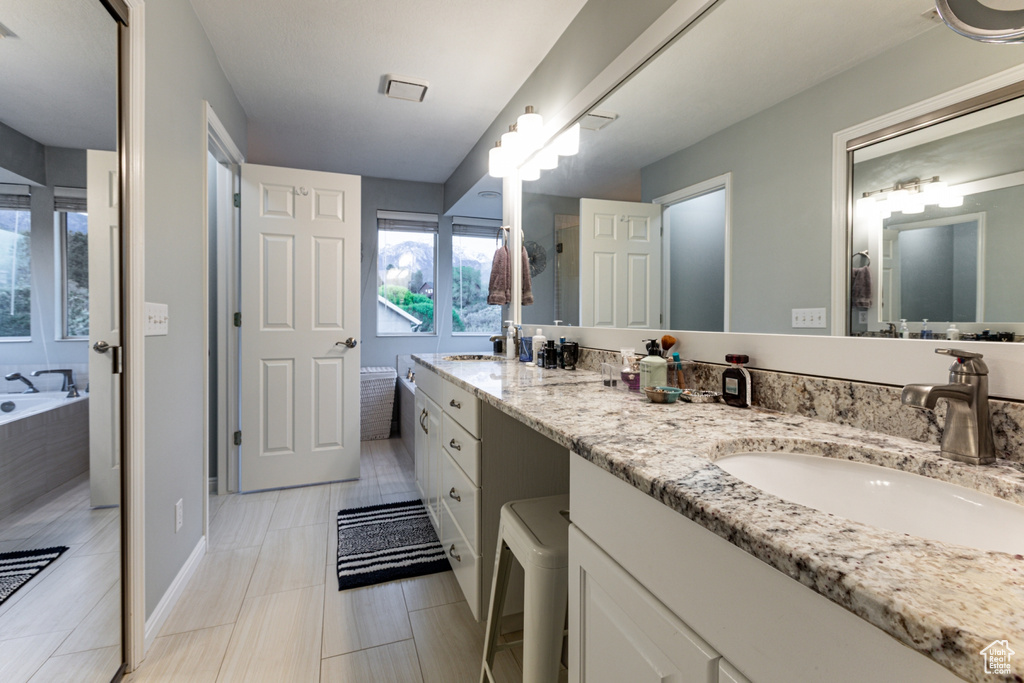 Bathroom featuring double vanity, a sink, and a bath