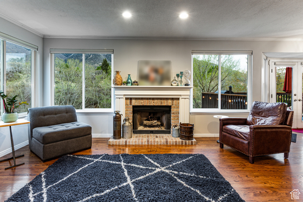 Living room with crown molding, wood finished floors, and a wealth of natural light