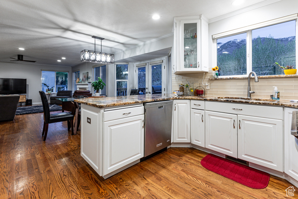 Kitchen featuring a sink, dark wood finished floors, a peninsula, white cabinetry, and stainless steel dishwasher