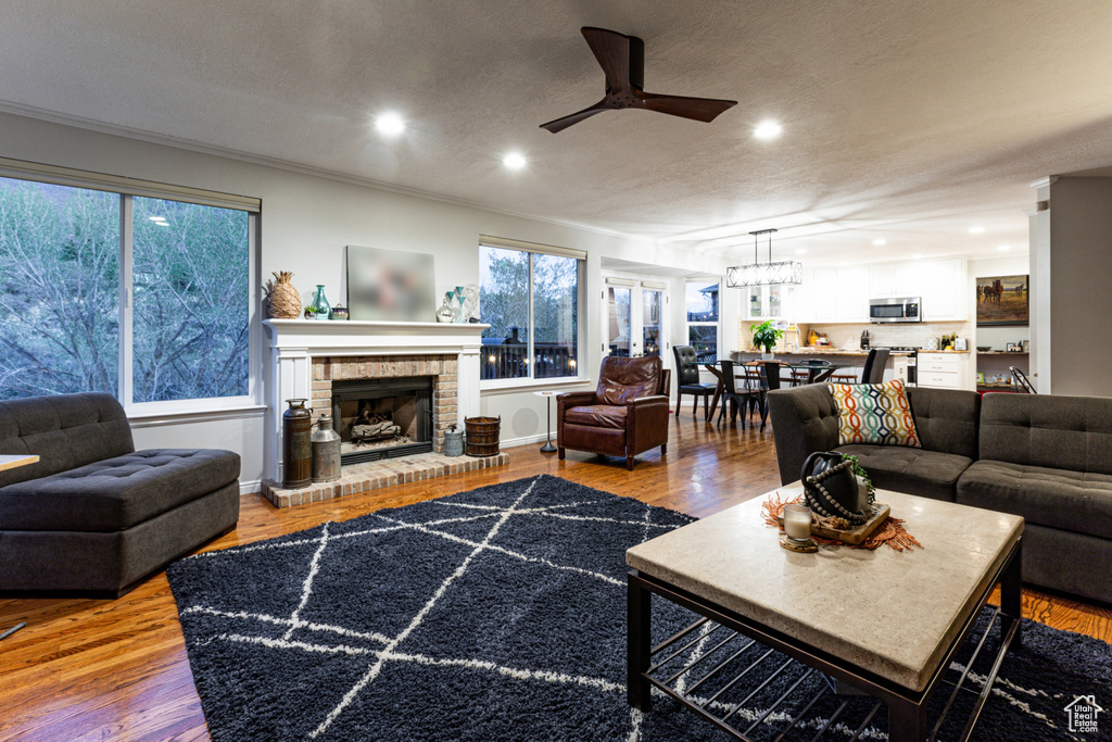 Living area with recessed lighting, wood finished floors, ceiling fan with notable chandelier, and a fireplace
