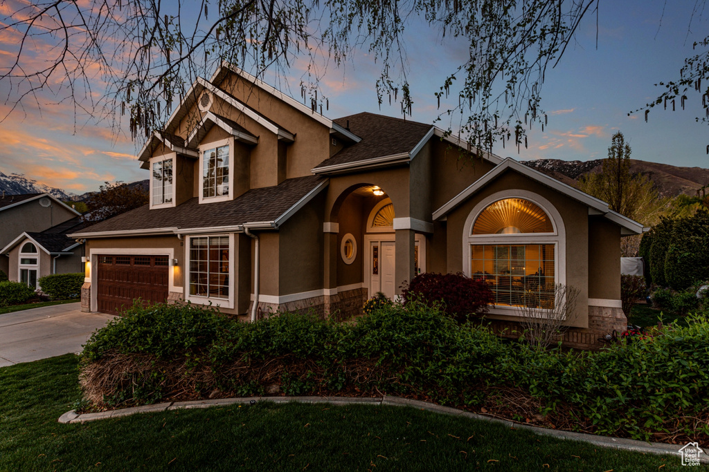 View of front of house with a mountain view, stucco siding, driveway, and stone siding