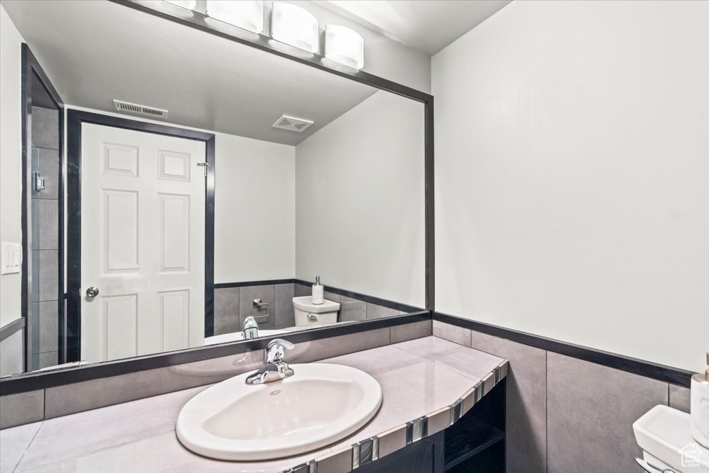 Bathroom featuring tile walls, visible vents, a wainscoted wall, and vanity