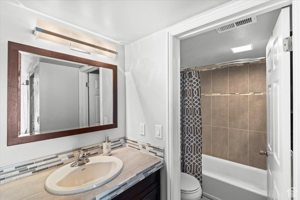 Bathroom with toilet, visible vents, shower / tub combo, and vanity