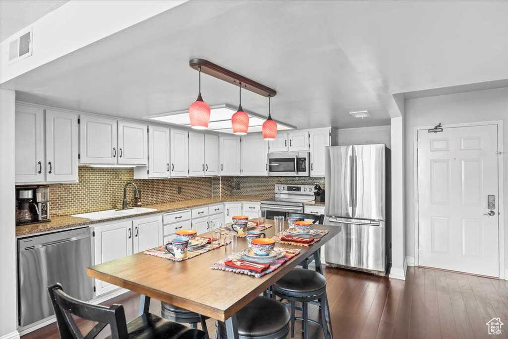Kitchen with white cabinets, stainless steel appliances, decorative backsplash, and a sink