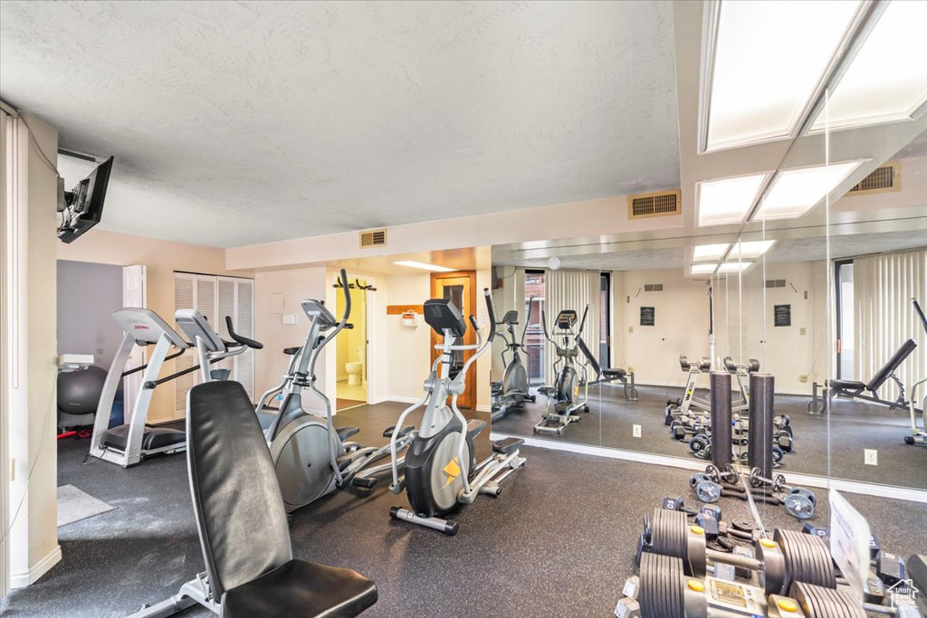 Workout area featuring visible vents, a textured ceiling, and baseboards