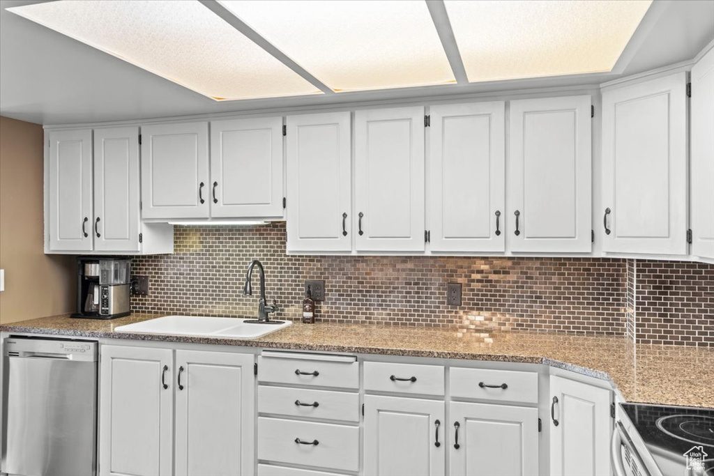 Kitchen with light countertops, decorative backsplash, a sink, and dishwasher