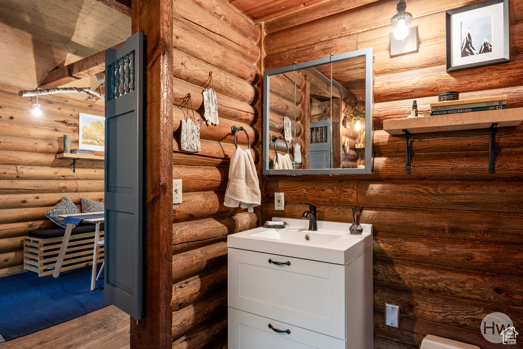 Bathroom featuring vanity, log walls, and wood finished floors