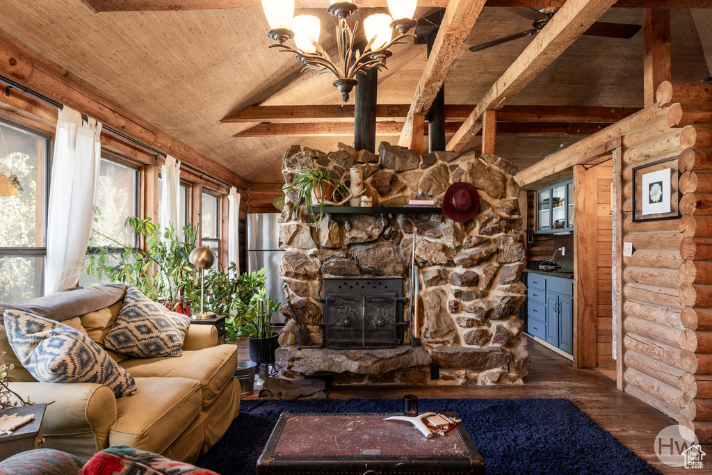 Living area featuring lofted ceiling with beams, log walls, wood finished floors, and wooden ceiling