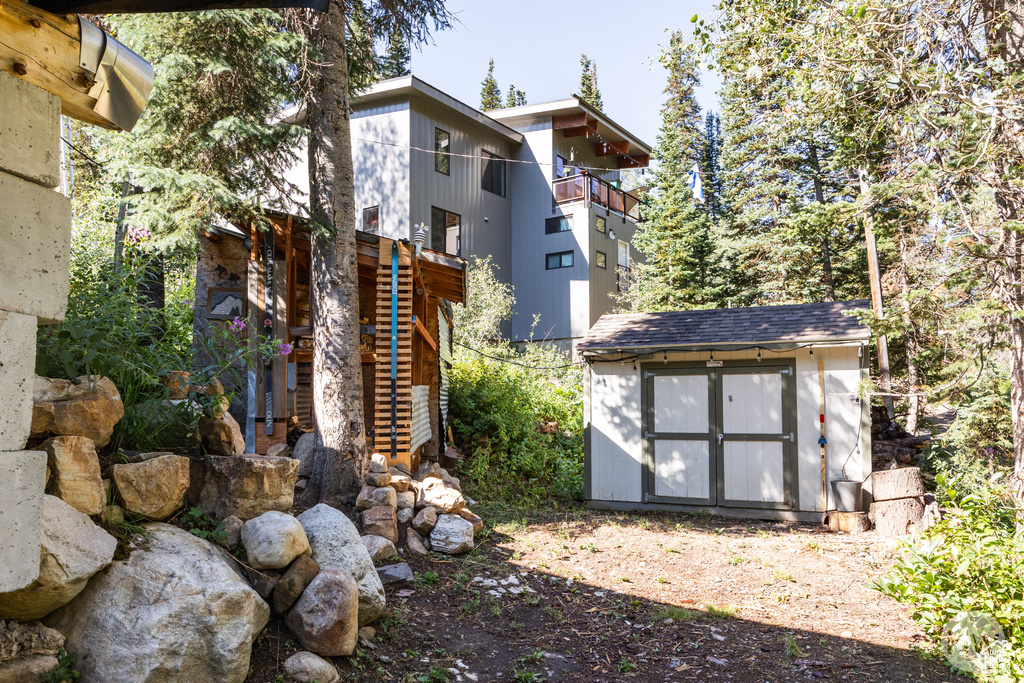 Rear view of house with a storage shed, an outdoor structure, and stairs