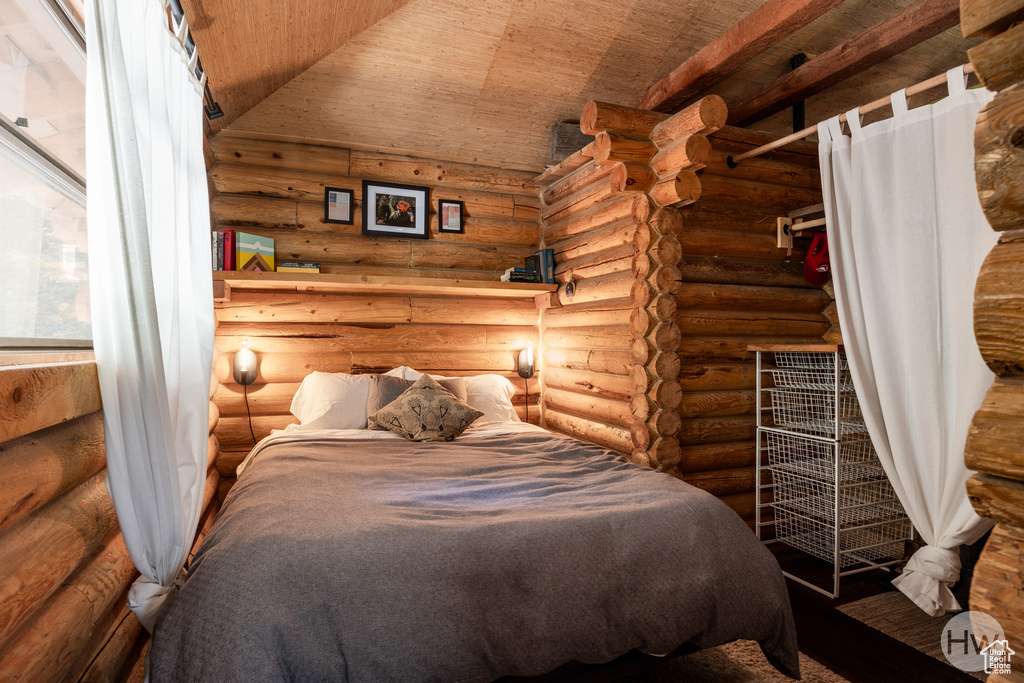 Bedroom with rustic walls and wooden ceiling