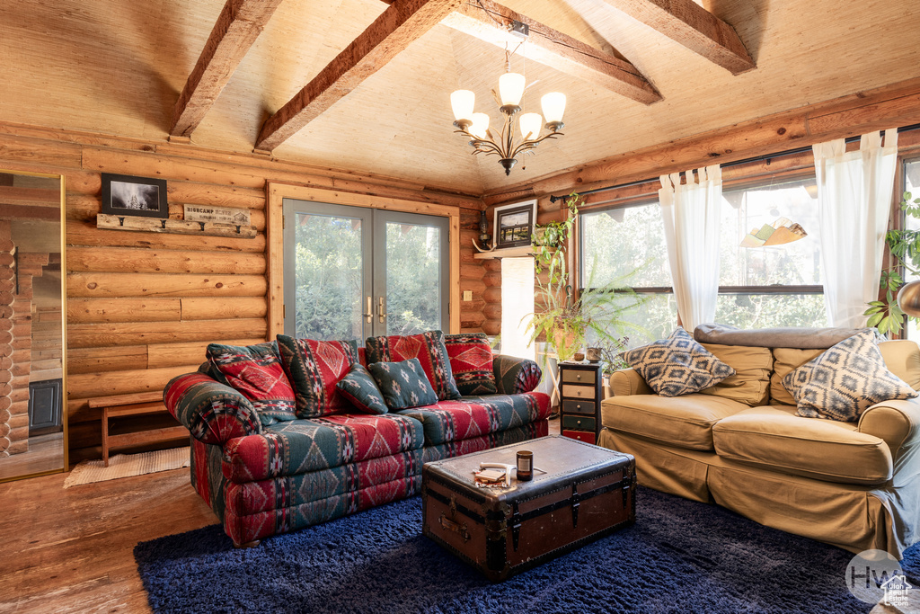 Living room with rustic walls, french doors, wood-type flooring, and a chandelier