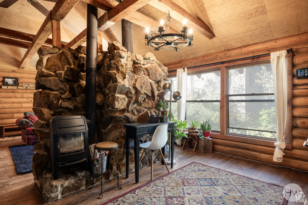 Interior space with a wood stove, beam ceiling, and a notable chandelier