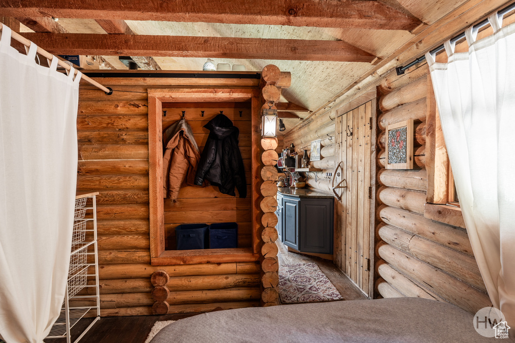 Interior space featuring rustic walls, beam ceiling, and wood finished floors