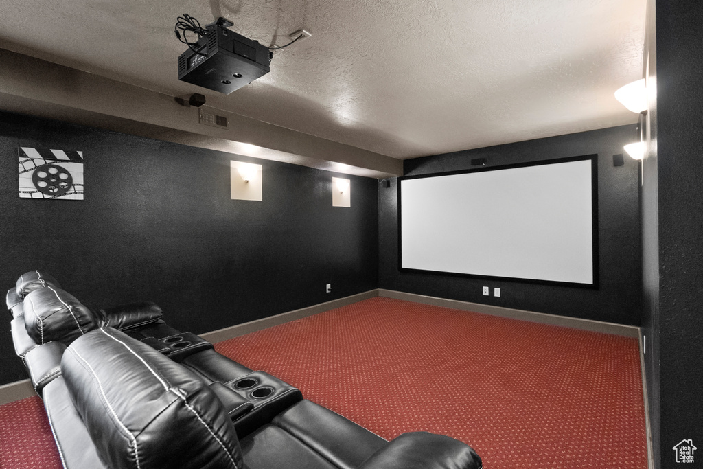 Carpeted cinema featuring a textured ceiling, baseboards, and visible vents