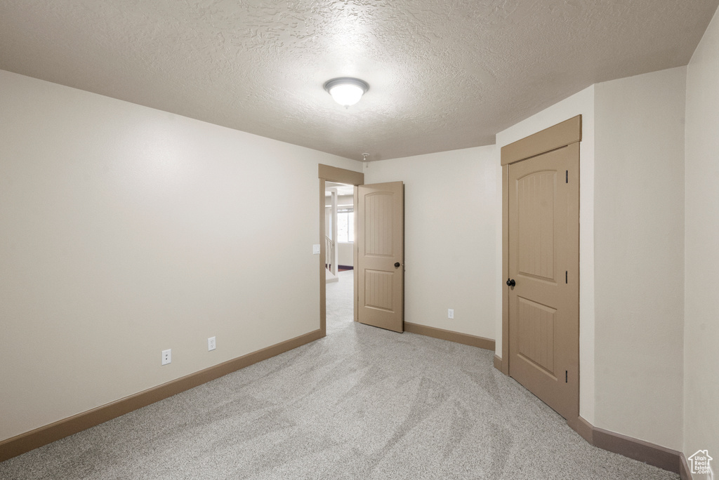 Carpeted empty room featuring baseboards and a textured ceiling
