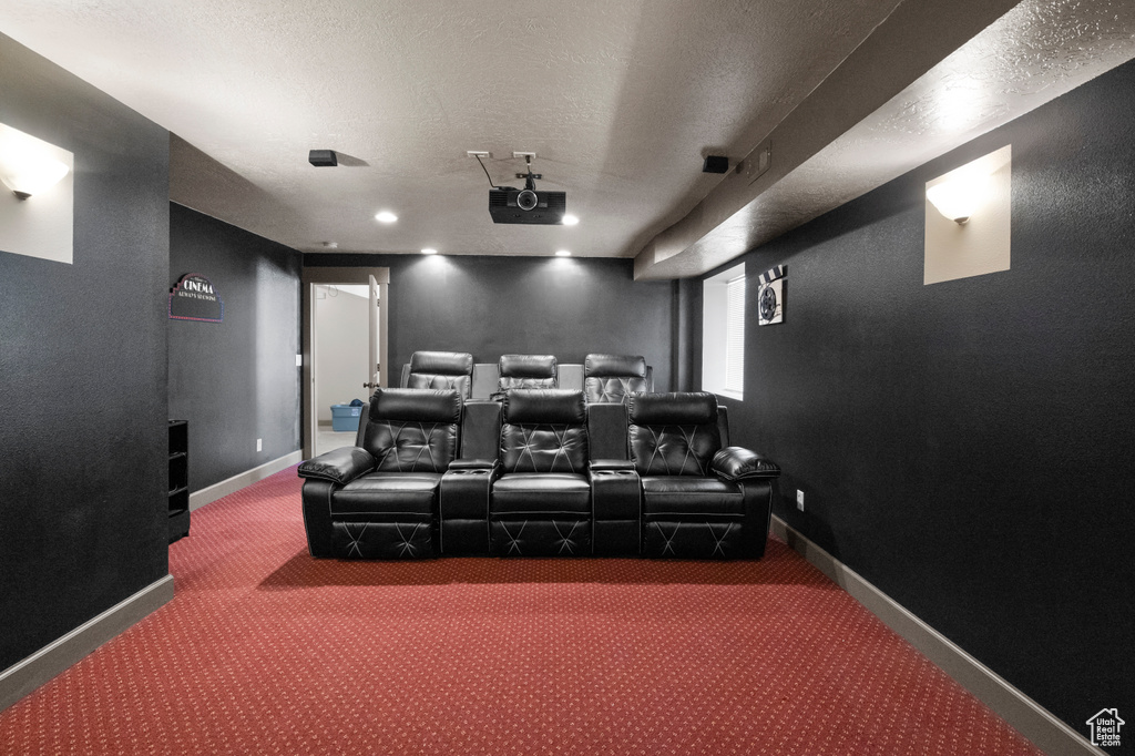 Carpeted cinema featuring a textured ceiling and baseboards