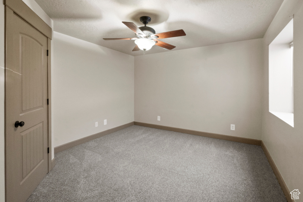 Empty room featuring baseboards, a ceiling fan, and light colored carpet