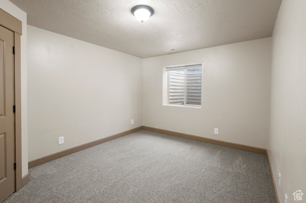 Carpeted empty room featuring baseboards and a textured ceiling