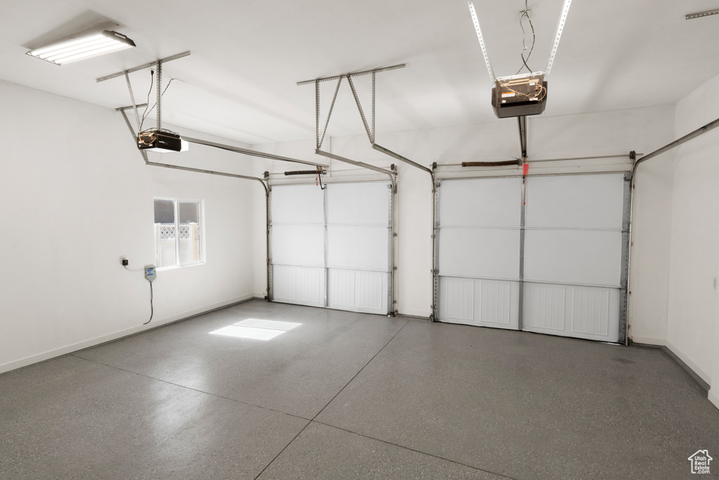 Garage featuring baseboards and a garage door opener