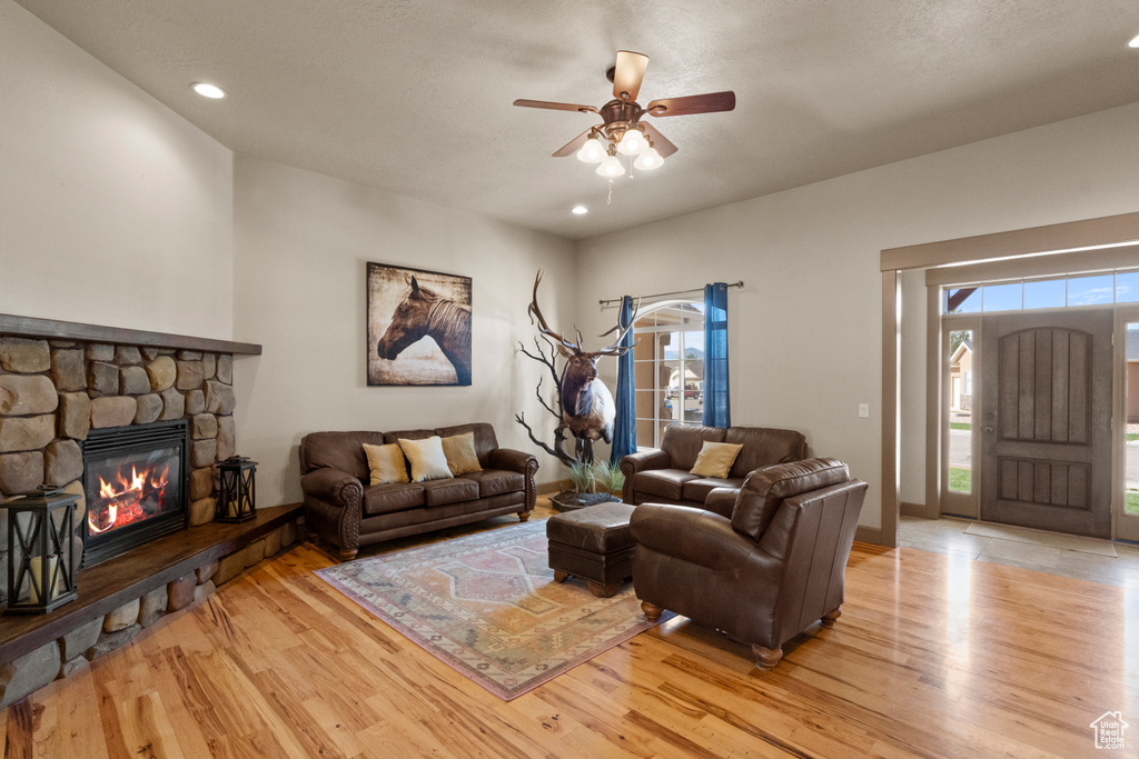 Living room featuring light wood-type flooring, a ceiling fan, recessed lighting, and a fireplace