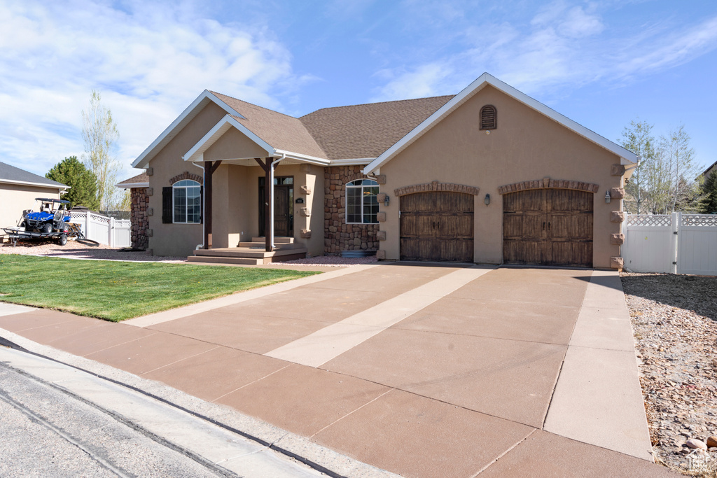 Ranch-style house with stucco siding, fence, stone siding, and a garage