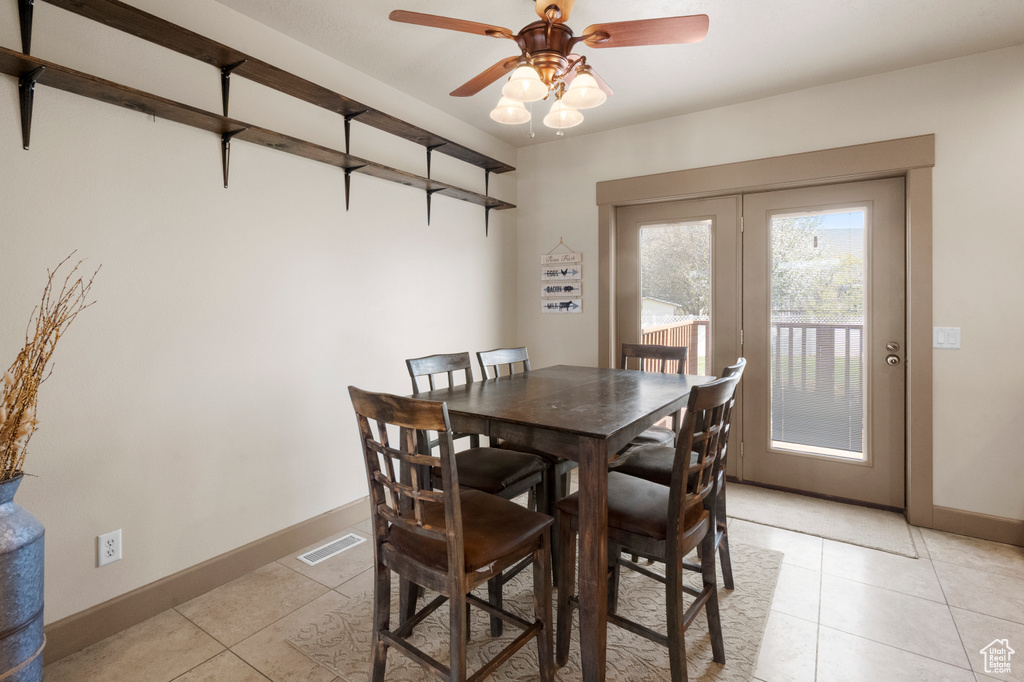 Dining space with light tile patterned flooring, baseboards, visible vents, and a ceiling fan