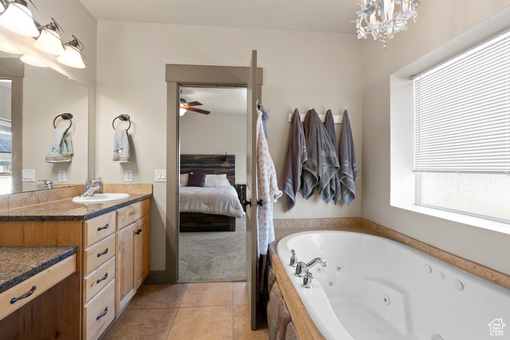 Bathroom with tile patterned flooring, vanity, a tub with jets, ceiling fan with notable chandelier, and ensuite bath