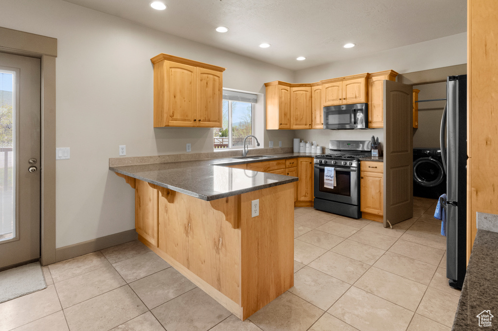 Kitchen with recessed lighting, a peninsula, a sink, and appliances with stainless steel finishes