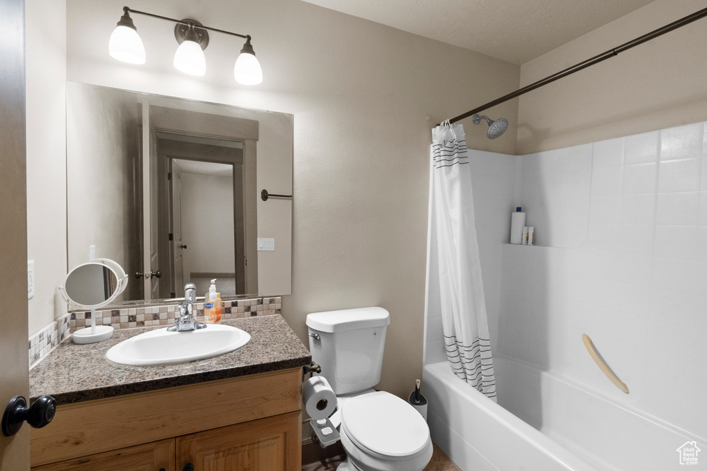 Full bathroom featuring vanity, decorative backsplash, toilet, and shower / tub combo