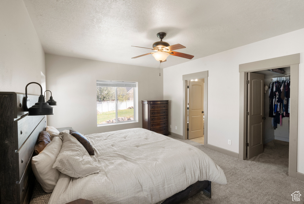 Bedroom featuring light colored carpet, baseboards, ceiling fan, and a spacious closet