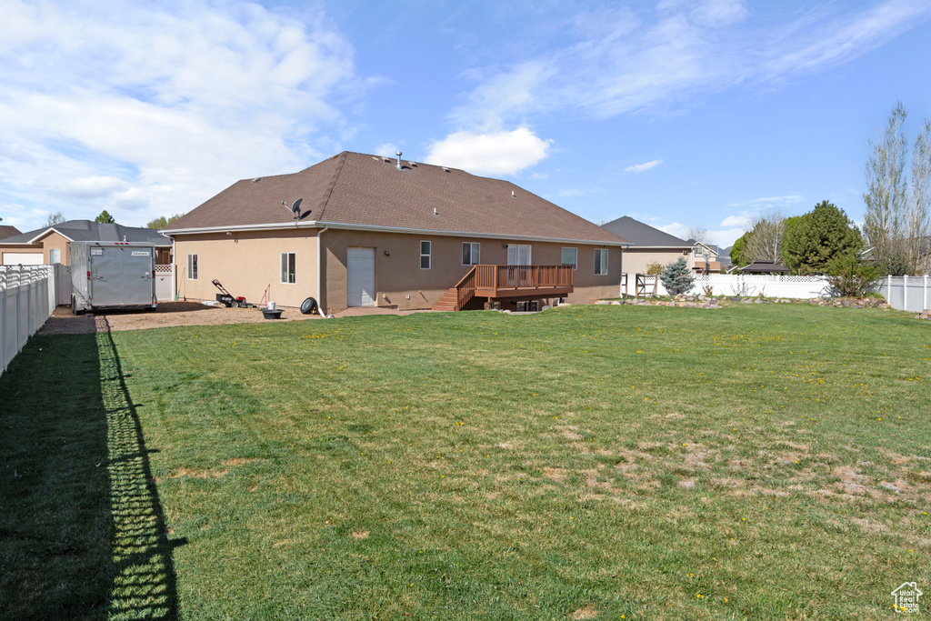 View of yard with a wooden deck, a patio, a fenced backyard, a storage unit, and an outbuilding