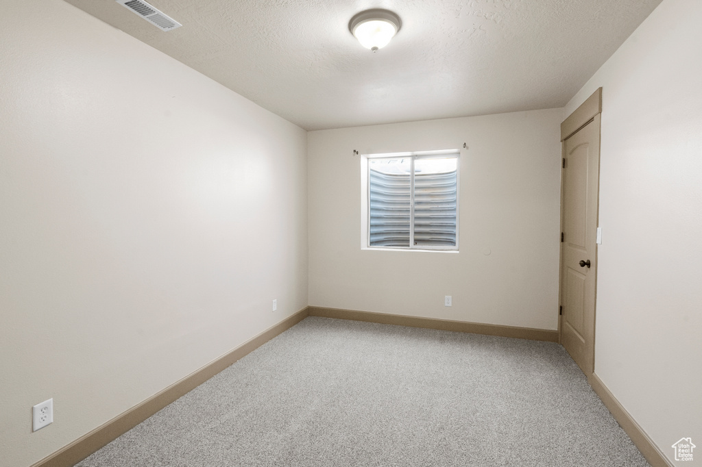 Spare room featuring baseboards, visible vents, and light colored carpet