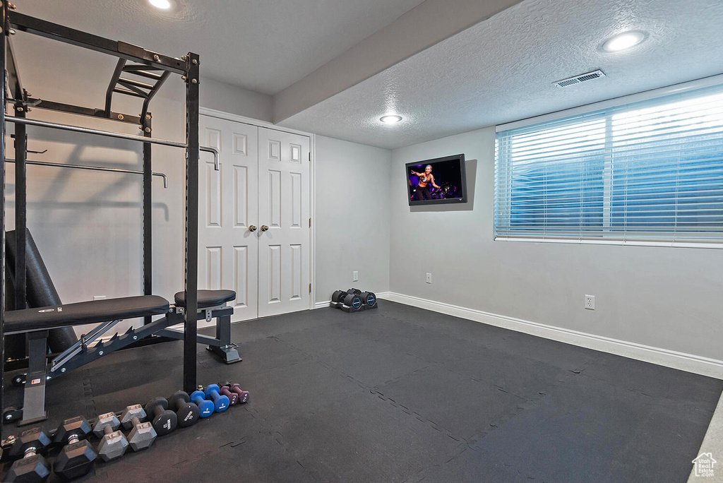 Workout area featuring visible vents, a textured ceiling, and baseboards