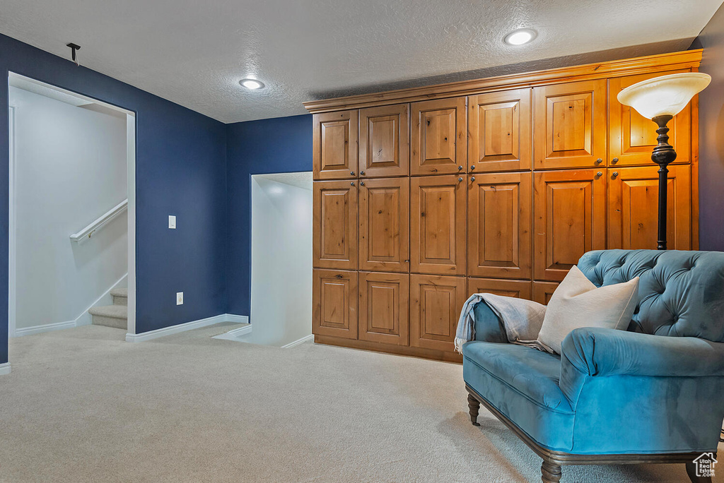 Sitting room featuring baseboards, carpet flooring, stairs, and a textured ceiling