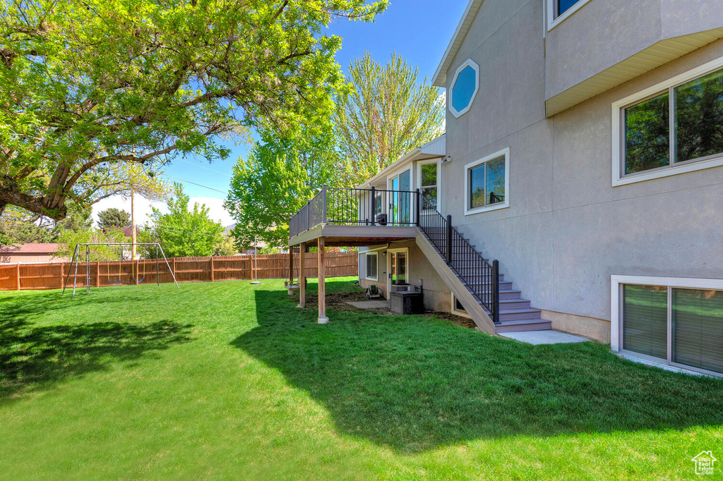 View of yard featuring stairs, a fenced backyard, a deck, and central AC unit