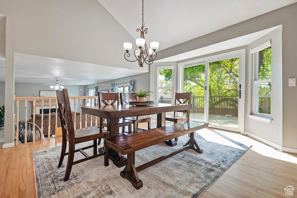Dining room with a notable chandelier, vaulted ceiling, light wood-type flooring, and a wealth of natural light