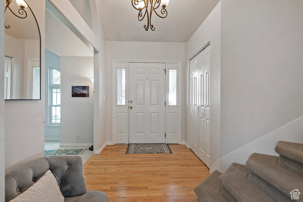 Foyer featuring baseboards, light wood finished floors, stairway, and an inviting chandelier