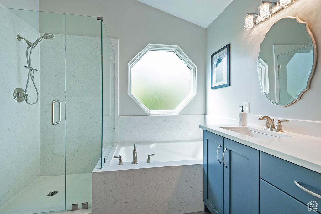 Full bath featuring vaulted ceiling, vanity, a shower stall, and a garden tub