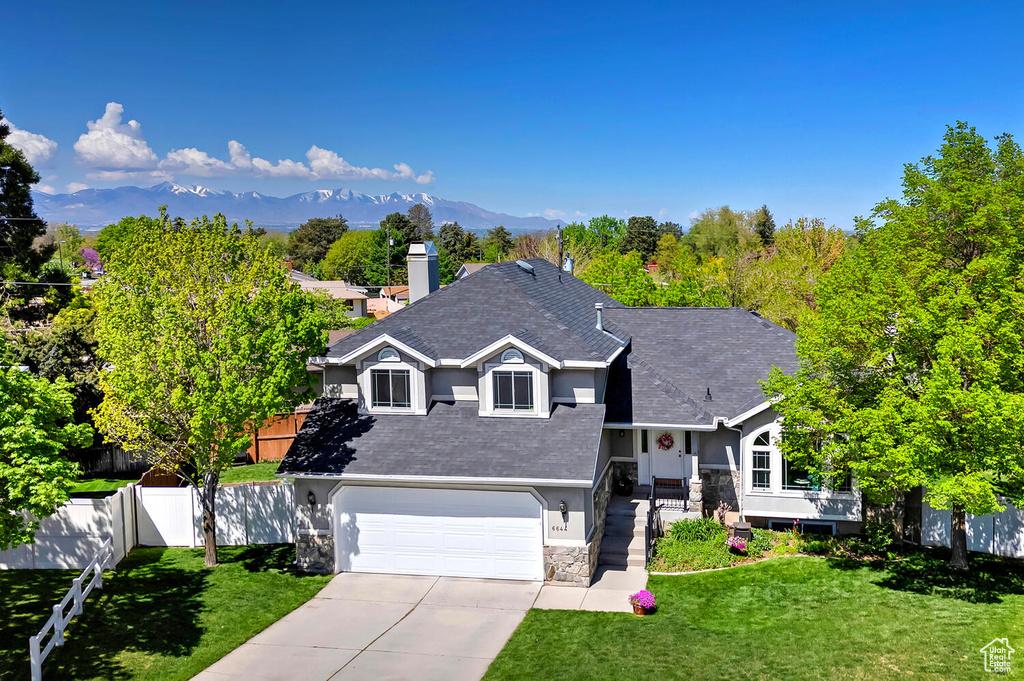 Tri-level home featuring fence, driveway, a front yard, and stucco siding