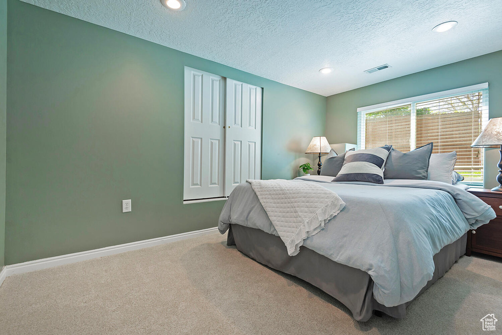 Bedroom featuring visible vents, a textured ceiling, and carpet