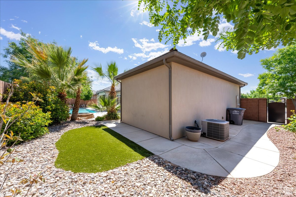 View of home's exterior with central AC unit, a patio area, fence, and a gate