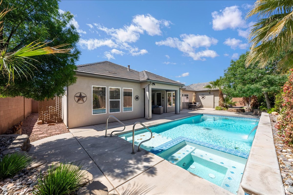View of swimming pool featuring a patio, a fenced backyard, and a pool with connected hot tub
