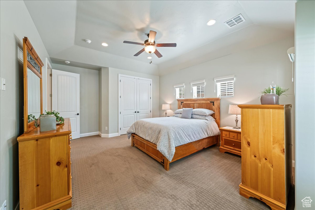 Bedroom with light carpet, recessed lighting, baseboards, a tray ceiling, and visible vents