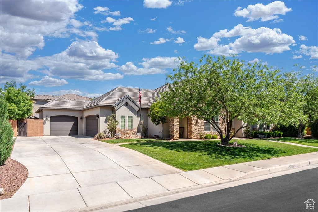 View of front of house with an attached garage, a front lawn, stone siding, stucco siding, and concrete driveway